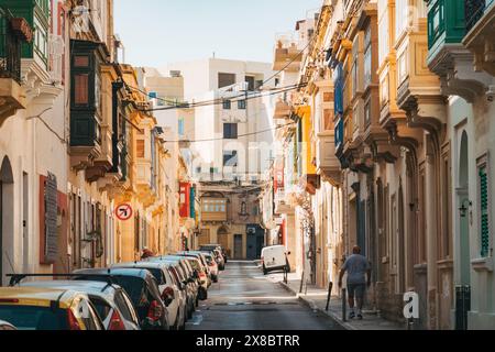 Une rue étroite bordée de maisons en calcaire et de balcons en bois avec fenêtres dans la ville Sliema, Malte Banque D'Images