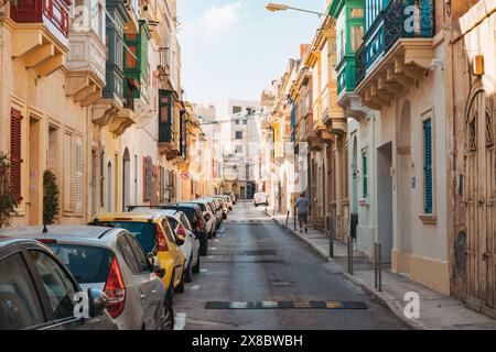 Une rue étroite bordée de maisons en calcaire et de balcons en bois avec fenêtres dans la ville Sliema, Malte Banque D'Images