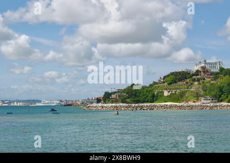 Un nageur dans la baie avec un ferry Brittany Ferries arrivant au port et l'Hôtel Real 5 étoiles au sommet de la colline sur la Costa Verde Santander Cantabria Espagne Banque D'Images