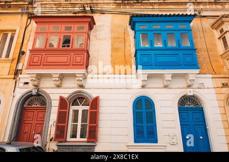 Portes voûtées peintes de couleurs vives et gallarija (fenêtre de balcon en bois) sur une maison en calcaire dans la ville de Sliema, Malte Banque D'Images