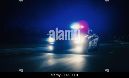 Voiture de patrouille de la circulation à la poursuite, conduite rapide avec sirènes flamboyantes dans les rues de la ville. Des officiers de la loi poursuivent un suspect. Les flics dans Squad car réagissent à l'appel d'urgence. Prise de vue nocturne cinématographique Banque D'Images