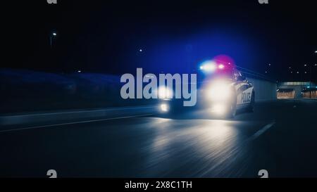 Voiture de patrouille de la circulation à la poursuite, conduisant rapidement avec des sirènes flamboyantes à travers le tunnel de la ville. Des officiers de la loi poursuivent un suspect. Les flics dans Squad car réagissent à l'appel d'urgence. Prise de vue nocturne cinématographique Banque D'Images