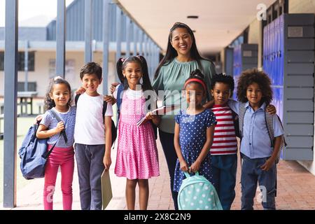 À l'école en plein air, un enseignant biracial d'âge moyen se tient avec six jeunes élèves Banque D'Images