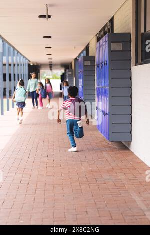 À l'école, des enfants divers marchent dans le couloir avec des casiers avec un espace de copie à l'extérieur Banque D'Images