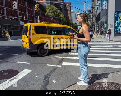 Gen Z’er avec pizza attend que la circulation s’estompe pour traverser la huitième Avenue à Chelsea à New York le mardi 21 mai 2024. (© Richard B. Levine) Banque D'Images