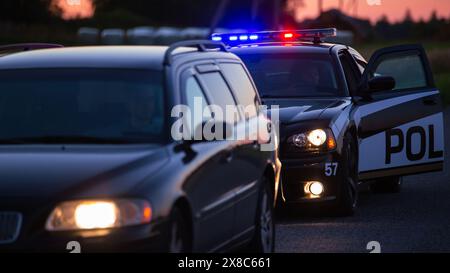 La voiture de patrouille de la circulation routière s'arrête sur le véhicule sur la route. Un officier de police de sexe masculin approche et demande au conducteur son permis et son enregistrement. Officier de la loi faisant son travail professionnellement. Grand angle cinématographique Banque D'Images