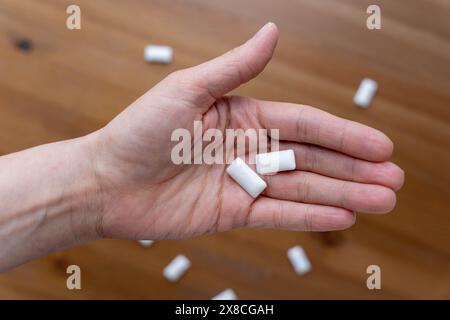 paume de femme tenant deux tampons de gomme à mâcher à la menthe, favorisant l'haleine fraîche et l'hygiène buccale. Concept de soins dentaires et de produits gommeux rafraîchissants. Banque D'Images