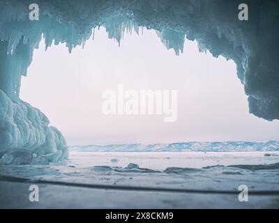 À l'intérieur d'une magnifique grotte de glace sur le lac Baïkal, de grands glaçons pendent du plafond, créant un paysage hivernal à couper le souffle. Les montagnes enneigées peuvent Banque D'Images