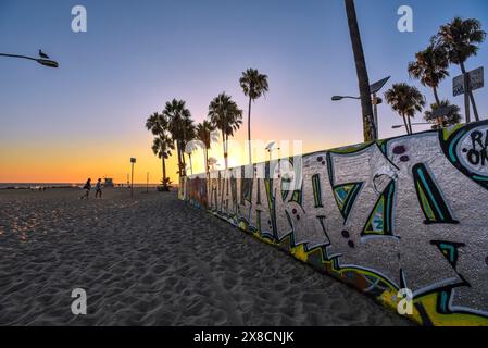 Un mur de béton rempli de graffitis colorés au coucher du soleil sur les Sables de Venice Beach, Californie Banque D'Images