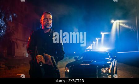 Portrait d'un policier masculin caucasien professionnel tenant une lampe de poche et un pistolet avec une voiture de police à l'arrière-plan. Officier héroïque gardant les citoyens et les civils en sécurité, luttant contre le crime Banque D'Images