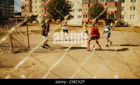 Jeunes garçons et filles multiethniques jouant au football dans le quartier. Happy Multicultural Kids jouant des Keep-ups, jonglant et contrôlant le Ball in the Air. Concept de Sports, enfance, amitié. Banque D'Images