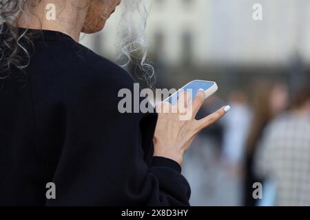 Mains féminines avec smartphone gros plan. Femme utilisant un téléphone portable dans une rue de la ville Banque D'Images