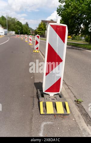 Rangée de panneaux de déviation de la circulation réfléchissants en rouge et blanc avec des stands jaunes. Scène de jour, bleu dky avec des nuages blancs. Banque D'Images