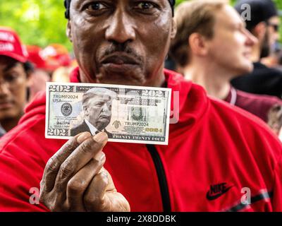 New York, New York, États-Unis. 23 mai 2024. Un homme montre Trump 2024 promotion qui a été faite pour ressembler à un billet de dollar américain. En dehors d’un rassemblement de Donald Trump dans le Bronx, New York, alors qu’un permis a été délivré pour 3 500 personnes, différents points de vente estiment la fréquentation allant de 4 000 à 35.000, déclenchant des conversations en raison de l’écart. En dehors de l'événement étiqueté se trouvaient des personnages des deux côtés, y compris des manifestants. (Crédit image : © Carlos Chiossone/ZUMA Press Wire) USAGE ÉDITORIAL SEULEMENT! Non destiné à UN USAGE commercial ! Banque D'Images