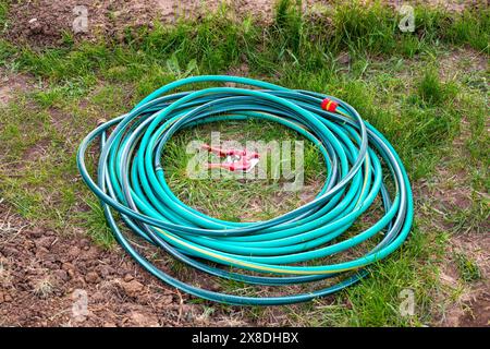 Tuyaux d'arrosage pour arroser roulés en rouleau, à côté d'un coupe-tuyau. Réparation des flexibles en caoutchouc. Banque D'Images