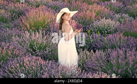 jeune fille joyeuse avec de la lavande dans le champ. Adolescente avec fleur de lavande debout dans le champ. adolescente avec lavande tenant un bouquet de fleurs Banque D'Images