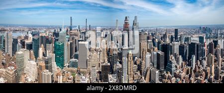 Admirez l'étalement impressionnant des gratte-ciels de Manhattan depuis un point de vue audacieux en contrebas. Des géants imposants traversent les nuages, offrant une vue unique. Banque D'Images