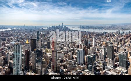 Admirez l'étalement impressionnant des gratte-ciels de Manhattan depuis un point de vue audacieux en contrebas. Des géants imposants traversent les nuages, offrant une vue unique. Banque D'Images