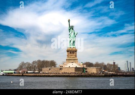 Lady Liberty illumine le chemin ! Capturez le symbole emblématique de la liberté, sa torche tenue haute contre un ciel bleu clair. Idéal pour le contenu de voyage et d'histoire. Banque D'Images