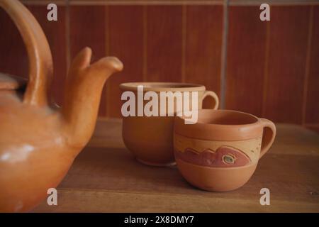 Bouilloire en faïence et tasses sur fond de table en bois. Banque D'Images