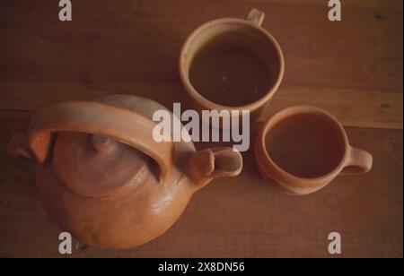 Bouilloire en faïence et tasses sur fond de table en bois. Banque D'Images