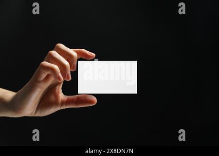 Femme avec carte de visite vierge sur fond noir, gros plan. Maquette pour le design Banque D'Images