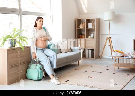 Jeune femme enceinte avec sacs d'hôpital de maternité à la maison Banque D'Images