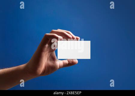 Homme avec carte de visite vierge sur fond bleu, gros plan. Maquette pour le design Banque D'Images