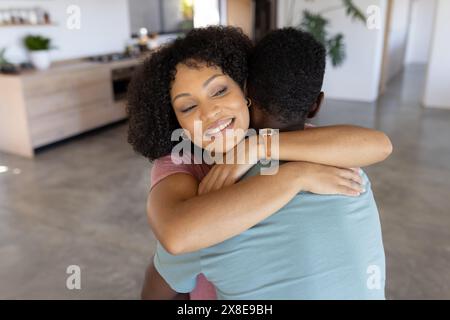 Couple diversifié embrassant à la maison, les deux souriants Banque D'Images