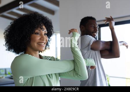 Un couple diversifié s'étirant ensemble à la maison dans une pièce lumineuse Banque D'Images