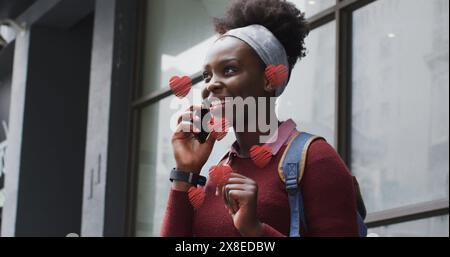 Petite amie/femme afro-américaine, portant un pull rouge, parlant au téléphone Banque D'Images