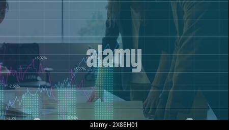 Groupe de collègues debout autour de la table dans le bureau, discutant des tableaux et des graphiques Banque D'Images