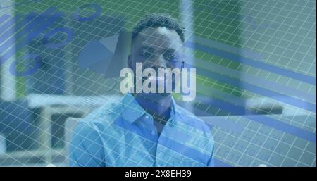 Image du traitement des données statistiques face au portrait d'homme afro-américain souriant au bureau Banque D'Images