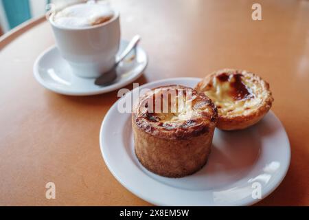 Gros plan de deux tartes à la crème anglaise portugaise, également connues sous le nom de Pastéis de Nata, servies sur une assiette blanche. Banque D'Images