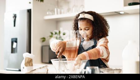 Fille, cuisson et mélange dans la cuisine à la maison ou la pâte, la maison et les compétences motrices ou le développement de l'enfance pour l'éducation culinaire. Cuisson, pâte à biscuits et Banque D'Images