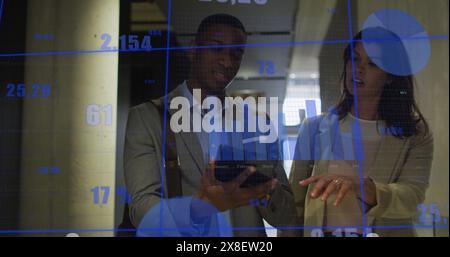 Image de graphiques, de chiffres changeants, de collègues discutant des rapports sur tablette numérique Banque D'Images