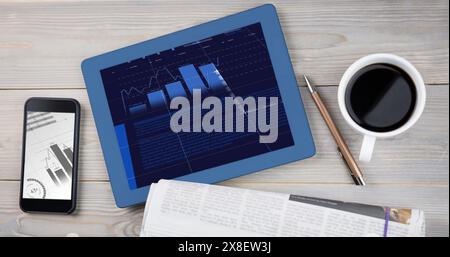 Appareils sur table affichant des graphiques financiers, à côté d'une tasse à café Banque D'Images