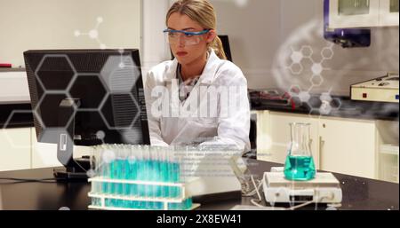 Sœur caucasienne portant des lunettes de sécurité, examinant l'ordinateur dans le laboratoire Banque D'Images