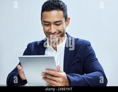 Tablette, sourire et homme d'affaires pour le défilement, l'écran tactile et l'agenda sur fond blanc. Personne responsable de la technologie, de l'entreprise et des finances, en ligne Banque D'Images