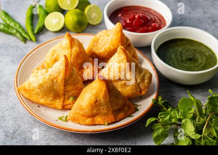 Sélection Focus Samosa, pâtisserie aux pommes de terre épicées, croustillante, salée et populaire en-cas indien servi avec des thés chutney à la tomate et à la menthe. Banque D'Images