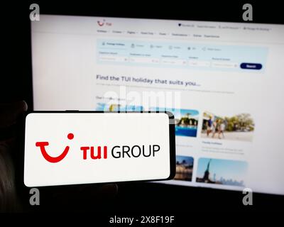 Personne tenant un smartphone avec le logo de la société allemande de voyage et de tourisme TUI AG en face du site Web. Concentrez-vous sur l'affichage du téléphone. Banque D'Images