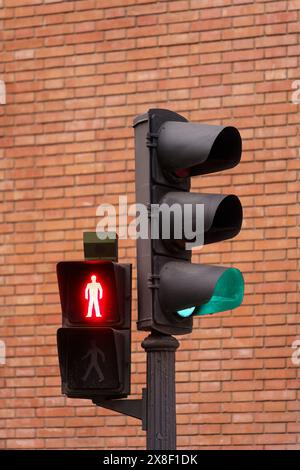 Feu de signalisation indiquant un signal piéton rouge contre le mur de briques rouges. Banque D'Images