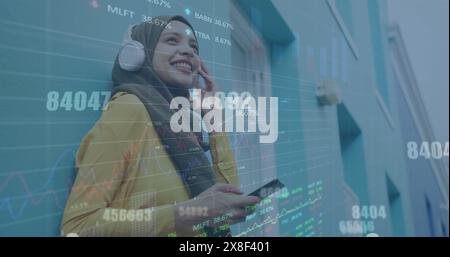 Image de traitement de données sur une femme en hijab portant des écouteurs écoutant de la musique dans la rue Banque D'Images