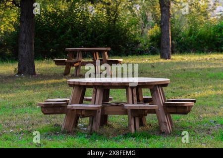 Tables rondes de pique-nique en bois dans un parc herbeux Banque D'Images