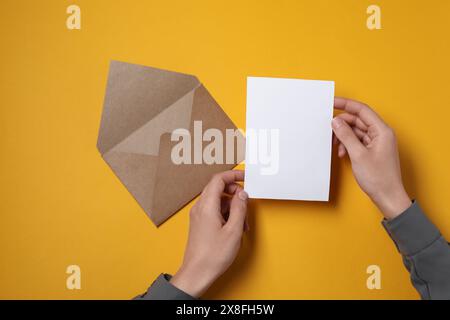 Femme avec carte vierge à la table orange, vue de dessus. Espace pour le texte Banque D'Images