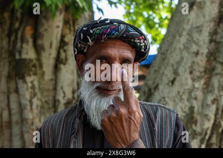 Anantnag, Inde. 25 mai 2024. Un électeur cachemiri montre son doigt marqué à l'encre après avoir voté devant un bureau de vote pendant la sixième phase des élections législatives indiennes à Pahalgam, dans le sud du Cachemire, district de la circonscription parlementaire d'Anantnag-Rajouri. Les élections législatives de 2024 à Lok Sabha (chambre basse du Parlement) marquent la première élection majeure au Jammu-et-Cachemire depuis que New Delhi a révoqué l'article 370, statut semi-autonome spécial de la région, et en a pris le contrôle direct en 2019. Crédit : SOPA images Limited/Alamy Live News Banque D'Images