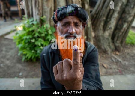 Anantnag, Inde. 25 mai 2024. Un électeur cachemiri montre son doigt marqué à l'encre après avoir voté devant un bureau de vote pendant la sixième phase des élections législatives indiennes à Pahalgam, dans le sud du Cachemire, district de la circonscription parlementaire d'Anantnag-Rajouri. Les élections législatives de 2024 à Lok Sabha (chambre basse du Parlement) marquent la première élection majeure au Jammu-et-Cachemire depuis que New Delhi a révoqué l'article 370, statut semi-autonome spécial de la région, et en a pris le contrôle direct en 2019. Crédit : SOPA images Limited/Alamy Live News Banque D'Images