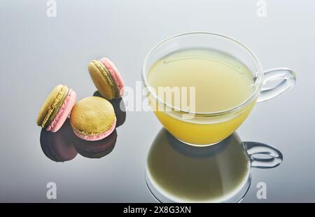 Une tasse de café se trouve sur la table, accompagnée d'une variété de macarons colorés. La nourriture et les verres créent un délicieux affichage des ingrédients dedans Banque D'Images