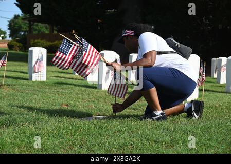 Raleigh, Caroline du Nord, États-Unis, 25 mai 2024; Courtney Crawford, de Raleigh, se joint à des bénévoles qui placent des drapeaux sur les pierres tombales de 6 000 au cimetière national de Raleigh avant le jour du souvenir. L'événement annuel, organisé par la Raleigh American Legion, honore les hommes et les femmes américains qui ont servi dans l'armée américaine en temps de paix et de guerre. Le cimetière national de Raleigh comprend les tombes des militaires de la guerre civile aux guerres d'Irak et d'Afghanistan. Credit d Guest Smith / Alamy Live News Banque D'Images