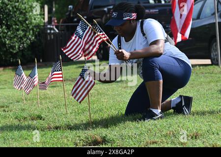 Raleigh, Caroline du Nord, États-Unis, 25 mai 2024; Courtney Crawford, de Raleigh, se joint à des bénévoles qui placent des drapeaux sur les pierres tombales de 6 000 au cimetière national de Raleigh avant le jour du souvenir. L'événement annuel, organisé par la Raleigh American Legion, honore les hommes et les femmes américains qui ont servi dans l'armée américaine en temps de paix et de guerre. Le cimetière national de Raleigh comprend les tombes des militaires de la guerre civile aux guerres d'Irak et d'Afghanistan. Credit d Guest Smith / Alamy Live News Banque D'Images